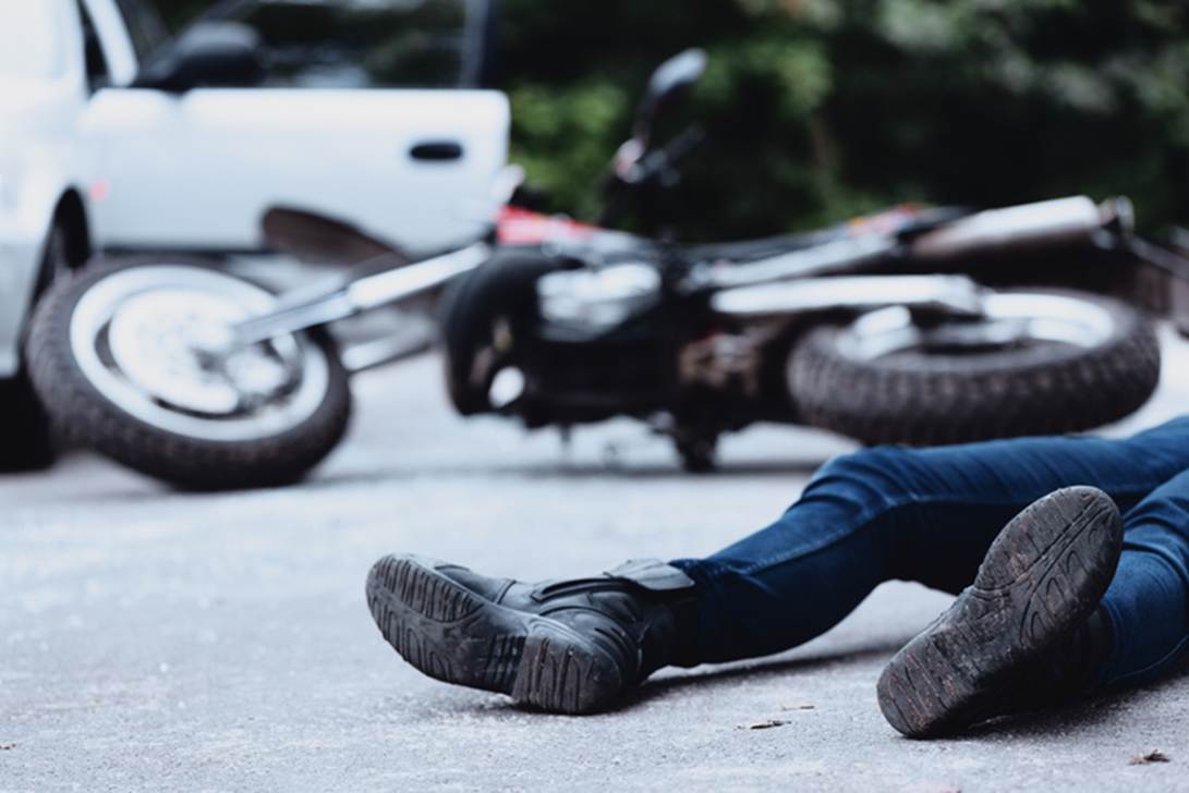 A person lying on the ground with a motorcycle

AI-generated content may be incorrect.